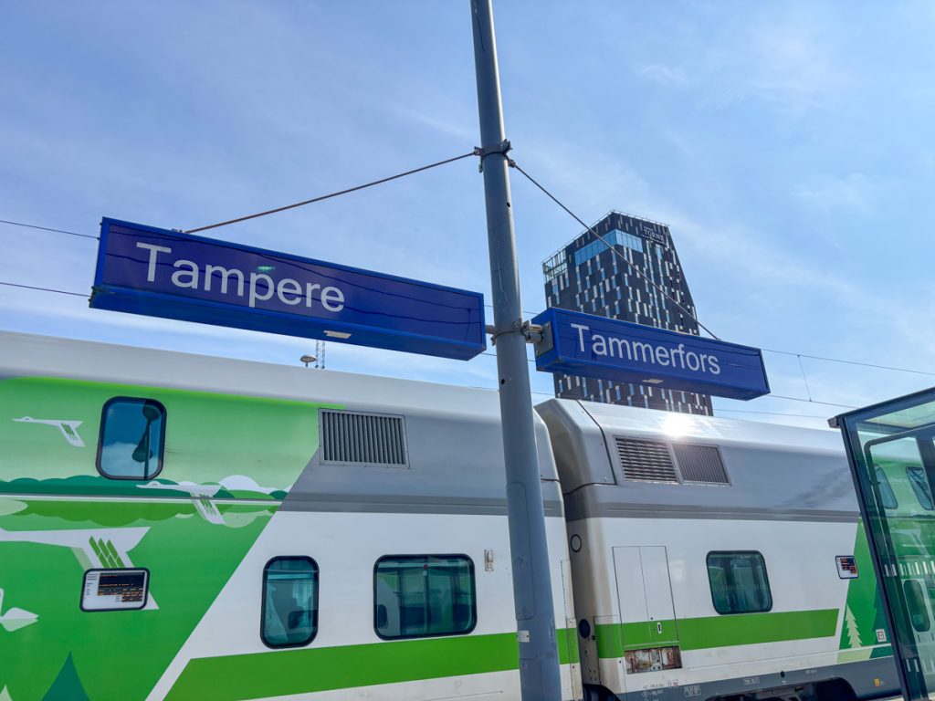 Train at Tampere Station with bilingual “Tampere” sign and Hotel Torni in the background.
