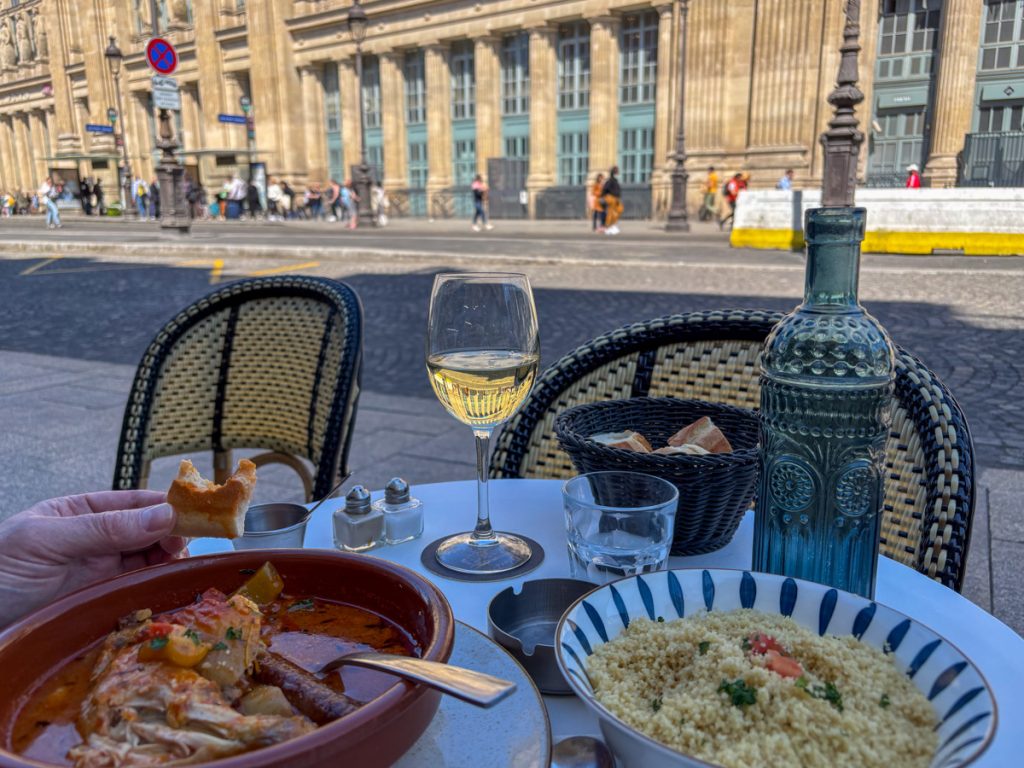 Food on the table, a glass of wine, and Gare du Nord in the background.